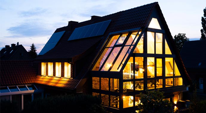 Außenansicht eines beleuchteten Wohnhauses mit großer Glasfront und moderner LED-Terrassenbeleuchtung bei Nacht.