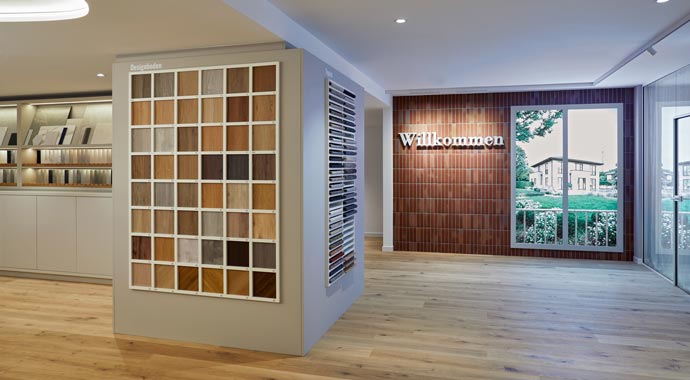Innenansicht des Viebrockhaus Flagship Store Berlin Charlottenburg mit Material Bemusterung fuer Parkett und Fliesen sowie Willkommen Schriftzug an Klinkerwand