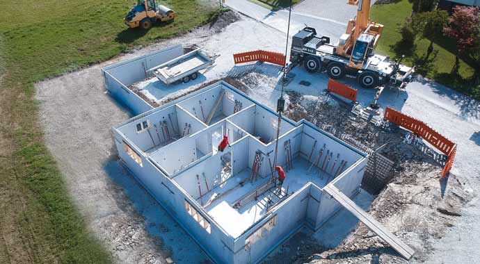 Bau eines modernen Beton-Kellers auf einer Baustelle Vogelperspektive einer Baustelle beim Bau eines Kellers aus Beton-Fertigteilen mit einem Mobilkran.