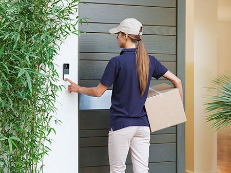 Postbotin betätigt die smarte Videotürklingel von Netatmo