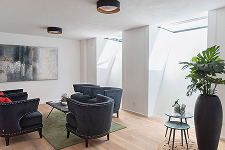 Hochwertig ausgebauter Keller als modernes Wohnzimmer Modern eingerichteter Wohnkeller mit dunklen Sesseln, Parkettboden und viel Tageslicht durch große Lichtschächte.