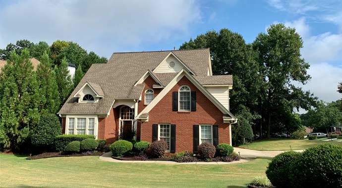 Braunes und weißes Betonhaus in der Nähe von grünen Bäumen unter blauem Himmel tagsüber